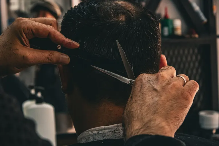 A barber’s hands working carefully with scissors and comb